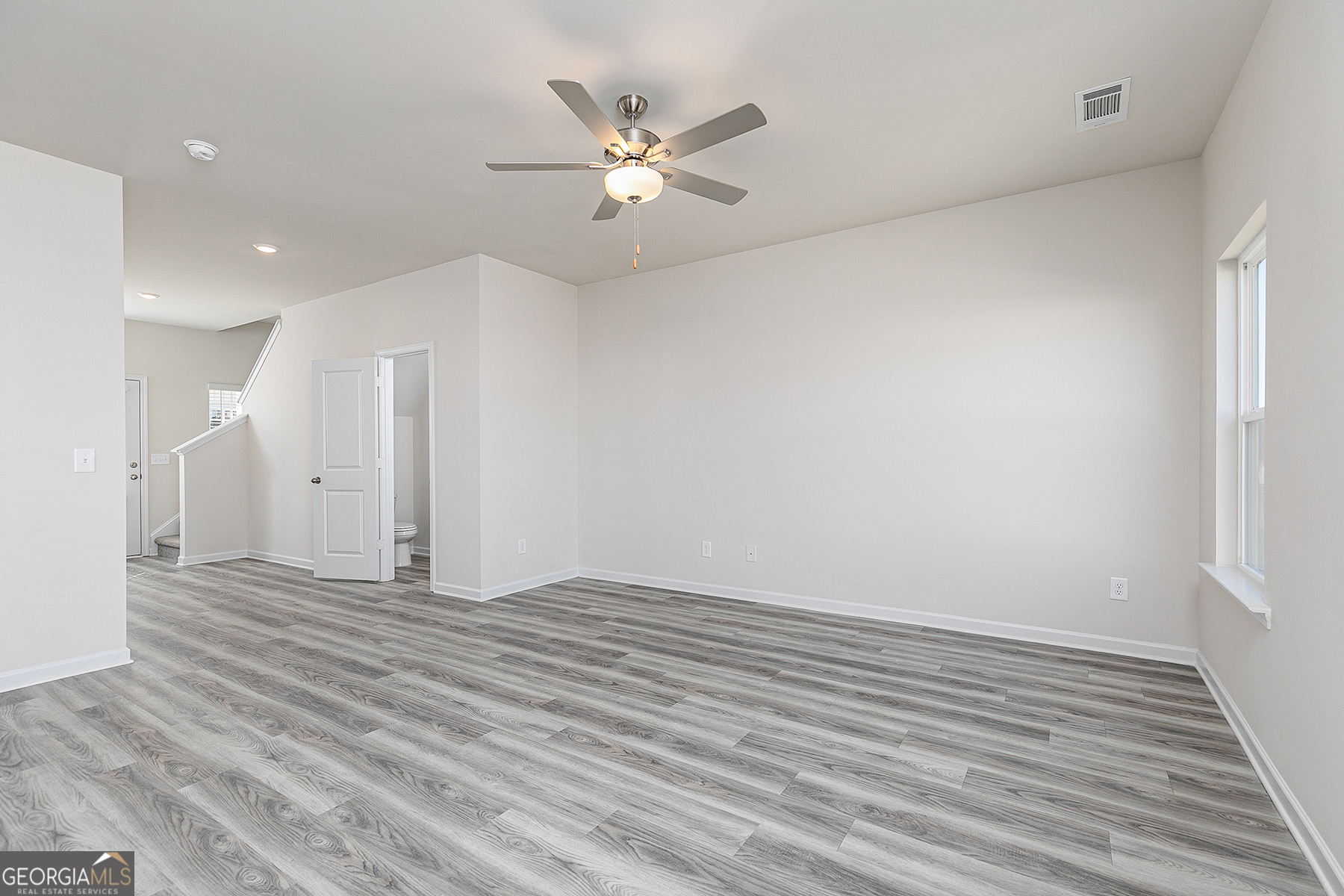 645 Mackenzie Cove Villa Rica, GA 30180 - Photo 4 of 20 a view of an empty room with wooden floor and a ceiling fan