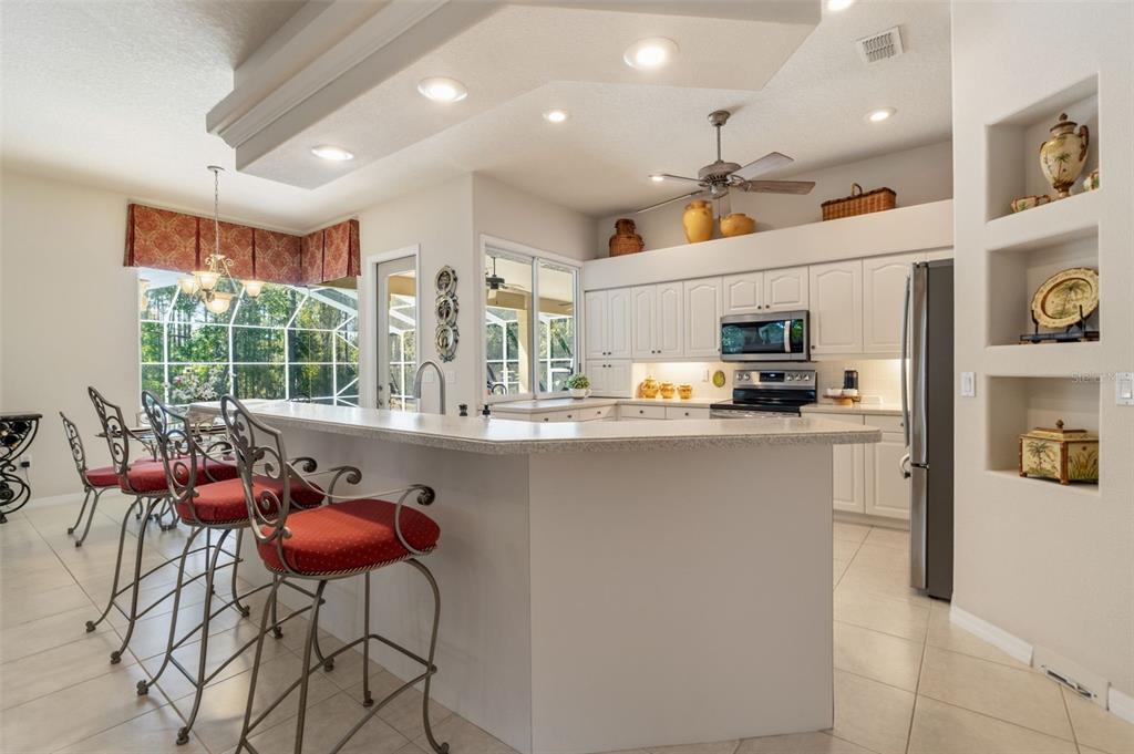 10260 Waters Edge Court Weeki Wachee, FL 34613 - Photo 27 of 58 a kitchen with stainless steel appliances kitchen island granite countertop a refrigerator a stove a sink dishwasher and white cabinets with wooden floor