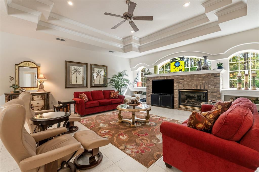 10260 Waters Edge Court Weeki Wachee, FL 34613 - Photo 8 of 58 a living room with furniture a fireplace a chandelier and a flat screen tv