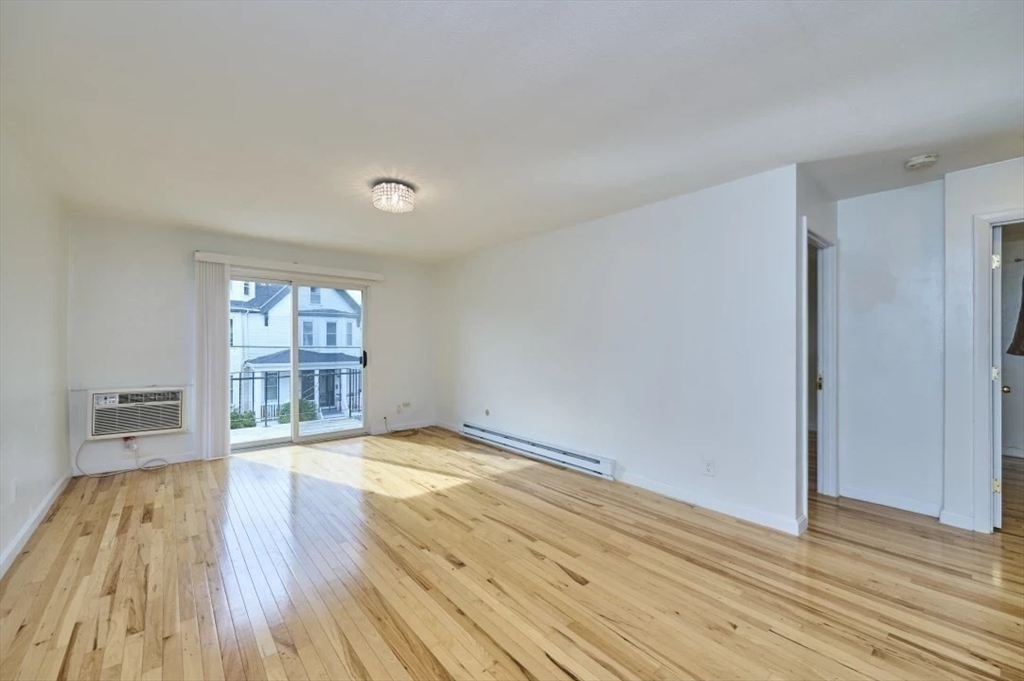 87 Cedar Street, Unit 10 Malden, MA 02148 - Photo 7 of 16 a view of an empty room with wooden floor and a window