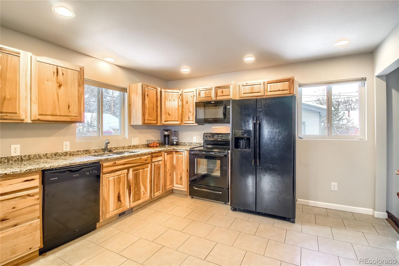 7545 Turner Drive Denver, CO 80221 - Photo 13 of 38 a kitchen with granite countertop a refrigerator a sink a stove top oven and cabinets