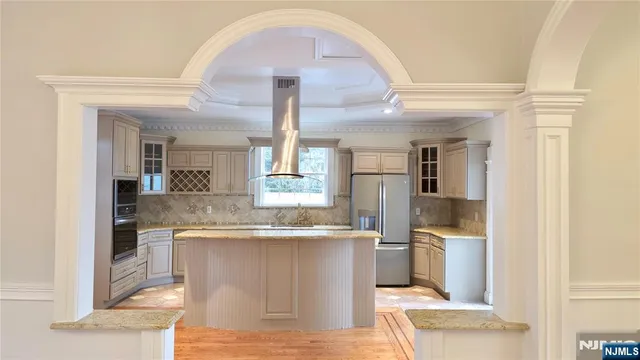 a living room with stainless steel appliances kitchen island granite countertop a sink and cabinets