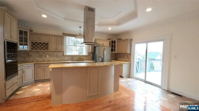 a kitchen with stainless steel appliances granite countertop a refrigerator a sink dishwasher a stove and white cabinets with wooden floor