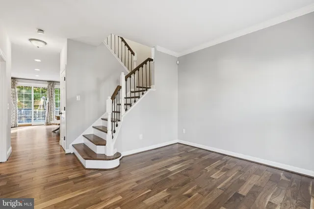 a view of an empty room with wooden floor and windows
