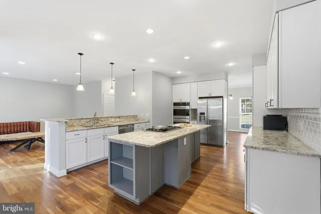 a large kitchen with stainless steel appliances kitchen island granite countertop a stove and a sink