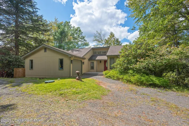 a view of a house with a yard and large tree