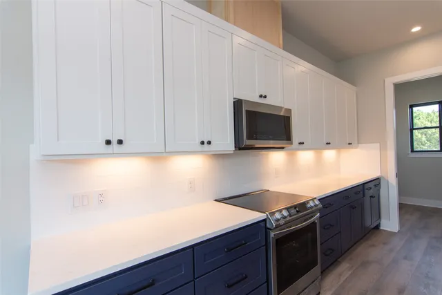 a view of a kitchen with kitchen island a sink wooden floor and a large window