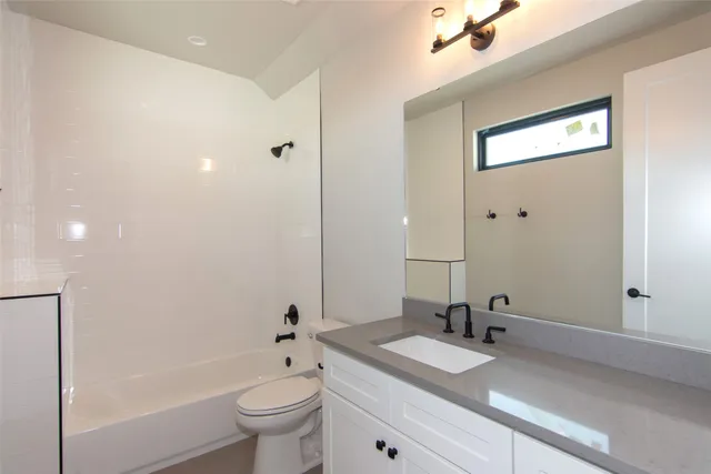 an empty room with wooden floor ceiling fan and windows