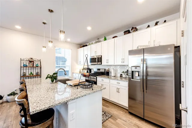 a kitchen with granite countertop a sink stainless steel appliances and white cabinets