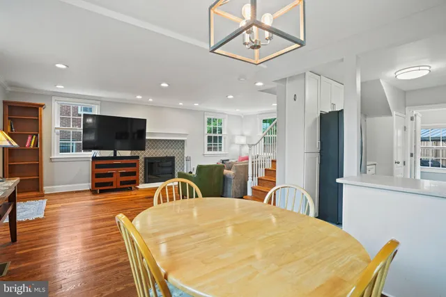 a living room with stainless steel appliances furniture a flat screen tv and kitchen view