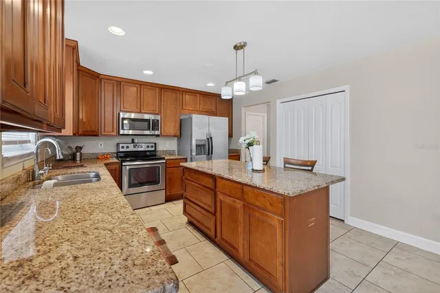 a kitchen with kitchen island granite countertop a sink counter top space appliances and cabinets
