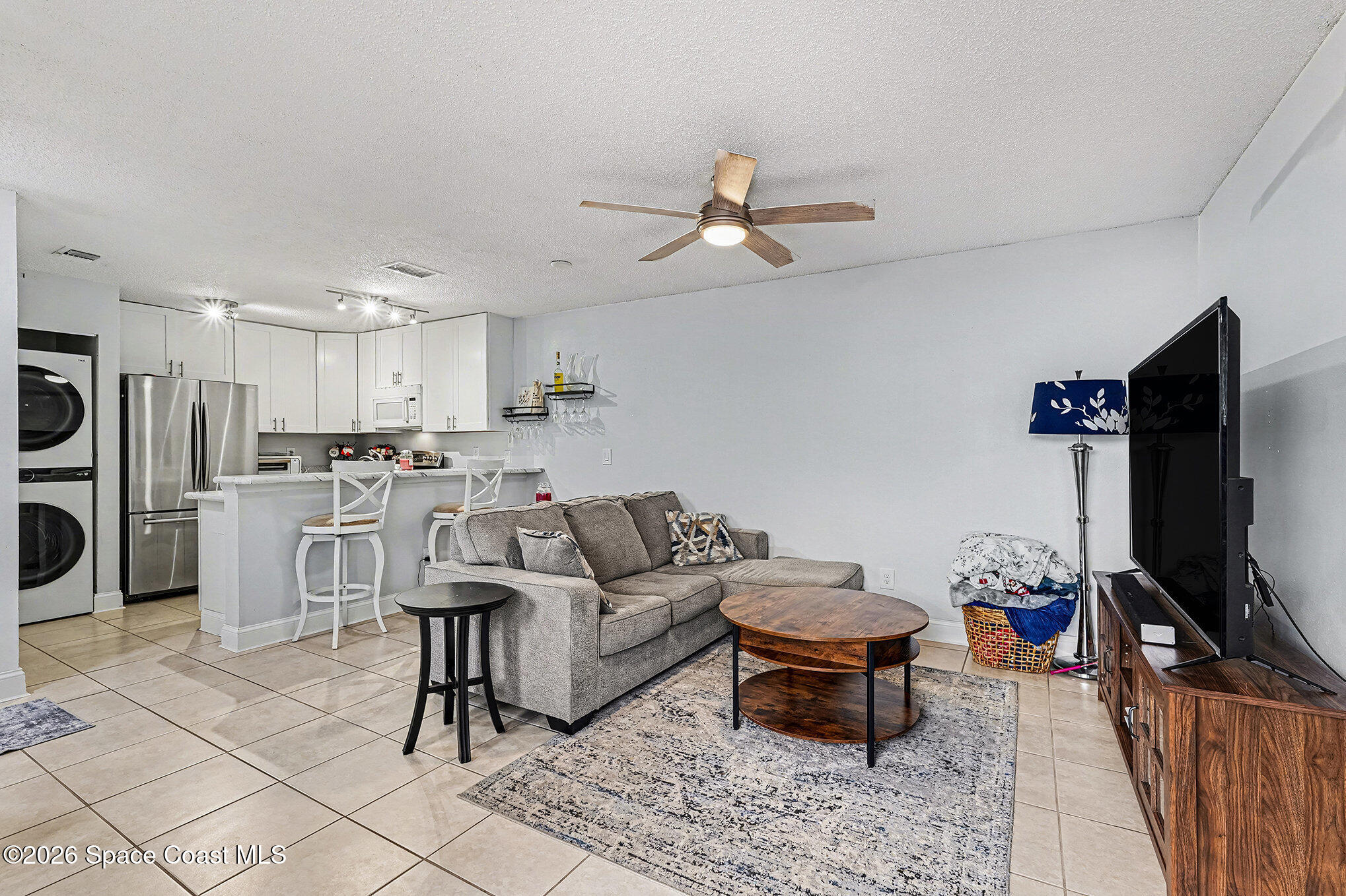 1491 Sheafe Avenue Northeast, Unit 104 Palm Bay, FL 32905 - Photo 3 of 19 a living room with furniture a flat screen tv and kitchen view