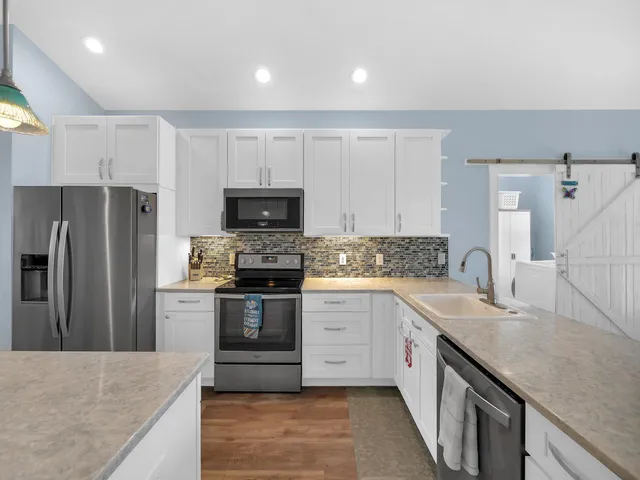 a kitchen with a sink a microwave a refrigerator and white cabinets