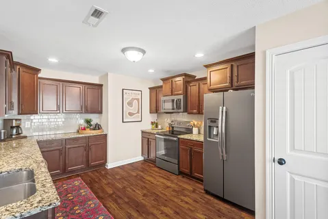 a kitchen with stainless steel appliances granite countertop a refrigerator and a stove top oven