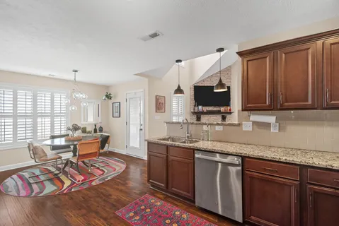 a kitchen with stainless steel appliances granite countertop a sink dishwasher stove and wooden cabinets with wooden floor