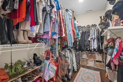 a view of walk in closet with clothes and shoes