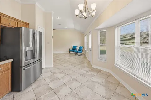 a view of a refrigerator in kitchen and an empty room with wooden floor windows