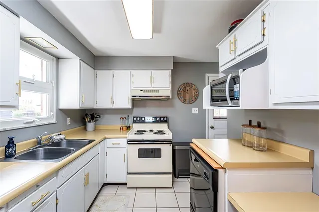 a kitchen with stainless steel appliances a sink a stove a microwave a refrigerator and cabinets