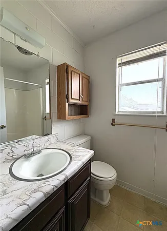 a bathroom with a granite countertop sink a toilet and a mirror