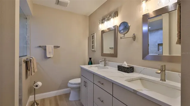 a bathroom with a granite countertop sink a toilet and a mirror