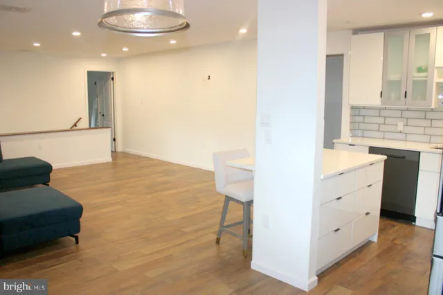 a living room with stainless steel appliances kitchen island granite countertop furniture and a wooden floor