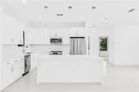 a kitchen with stainless steel appliances a refrigerator sink stove and white cabinets