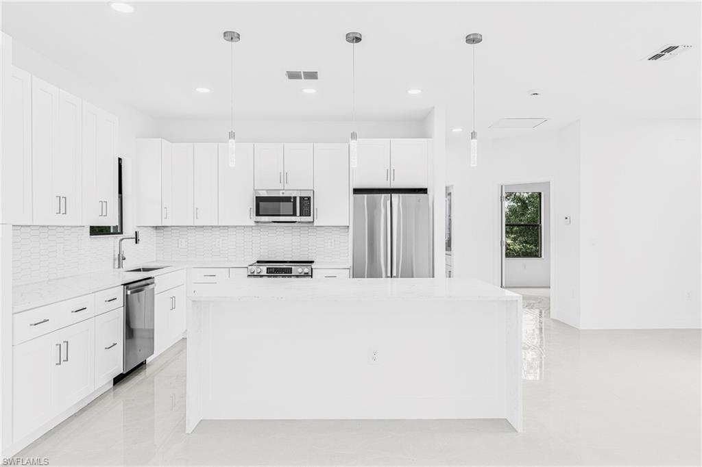 343 Pullman Street Lehigh Acres, FL 33974 - Photo 11 of 48 a kitchen with stainless steel appliances a refrigerator sink stove and white cabinets