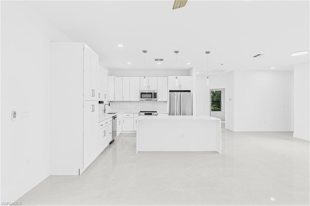 343 Pullman Street Lehigh Acres, FL 33974 - Photo 12 of 48 a white kitchen with cabinets and a refrigerator