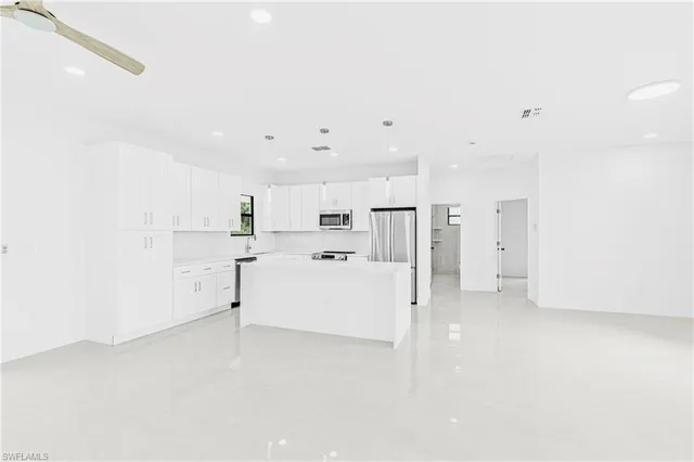 a view of a kitchen with refrigerator and white cabinets
