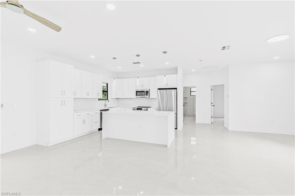 343 Pullman Street Lehigh Acres, FL 33974 - Photo 13 of 48 a view of a kitchen with refrigerator and white cabinets