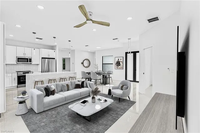 a living room with furniture kitchen view and a wooden floor