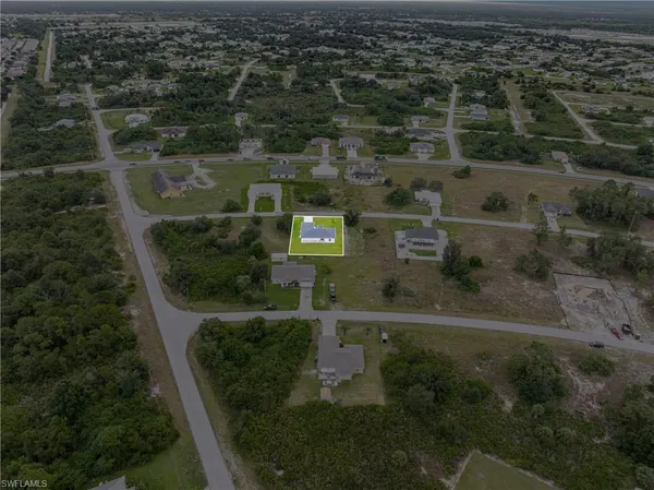 an aerial view of residential houses with outdoor space and trees