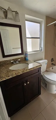 a bathroom with a granite countertop sink toilet and mirror