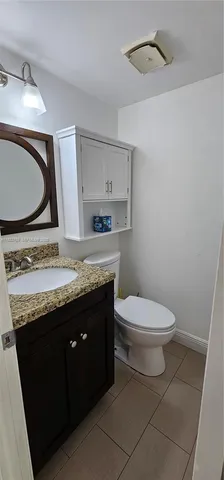 a bathroom with a granite countertop toilet sink mirror and vanity