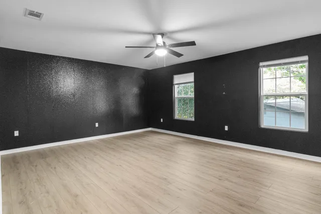 a view of an empty room with a window and wooden floor