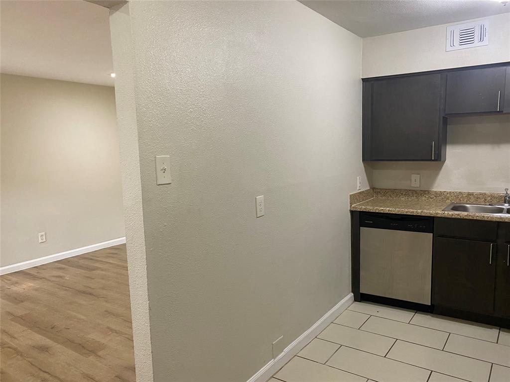 4618 Reiger Avenue, Unit 112 Dallas, TX 75246 - Photo 5 of 13 Kitchen featuring stainless steel dishwasher, a textured wall, and dark cabinets
