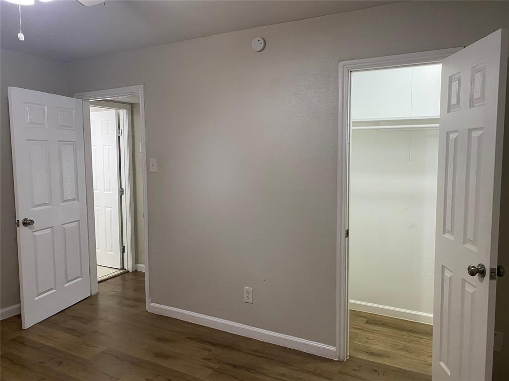 4618 Reiger Avenue, Unit 112 Dallas, TX 75246 - Photo 7 of 13 Unfurnished bedroom with dark wood finished floors and a walk in closet