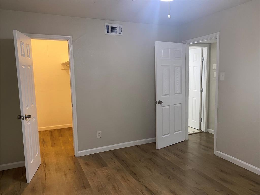 4618 Reiger Avenue, Unit 112 Dallas, TX 75246 - Photo 9 of 13 Unfurnished bedroom featuring a spacious closet and dark wood-style floors