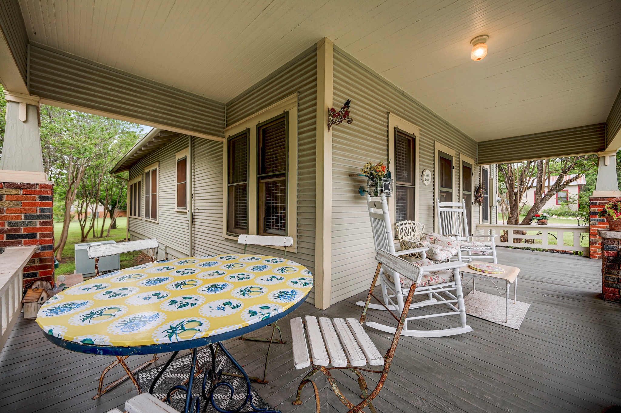 719 Elm Street Blanco, TX 78606 - Photo 6 of 25 Expansive covered porch featuring a painted wood floor, beadboard ceiling, and brick column accents