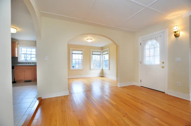 a view of a living room with wooden floor and a kitchen