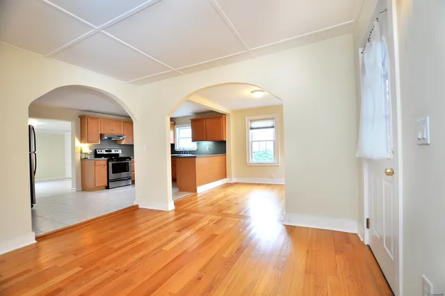 a view of a kitchen with kitchen island wooden floors stainless steel appliances