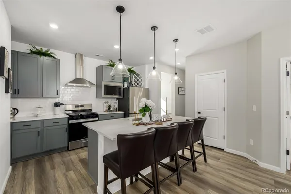 a kitchen with stainless steel appliances granite countertop a sink a stove a dining table and chairs