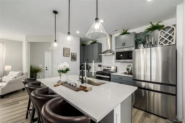a kitchen with stainless steel appliances kitchen island granite countertop a dining table chairs and a refrigerator