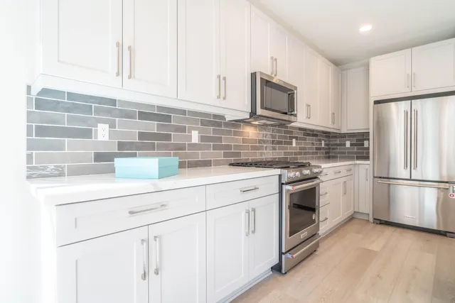 a large kitchen with stainless steel appliances kitchen island granite countertop a sink and cabinets