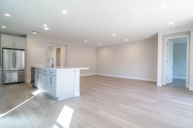 a view of kitchen with granite countertop refrigerator oven sink and white cabinets with wooden floor