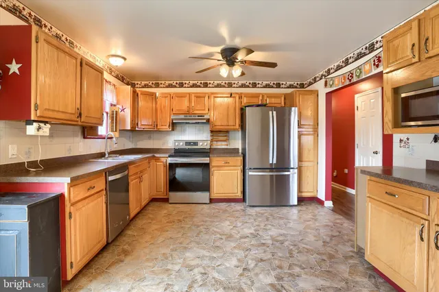 a kitchen with stainless steel appliances granite countertop a refrigerator a sink dishwasher a stove with wooden cabinets and floor