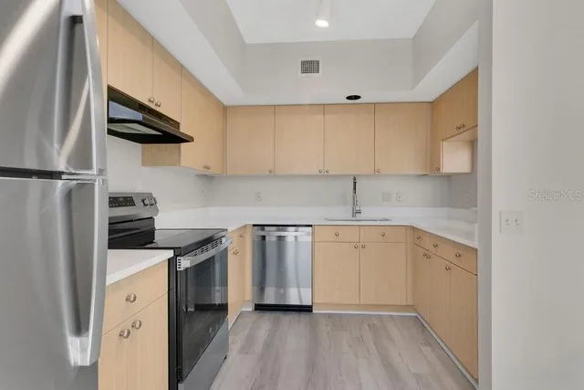 a kitchen with a sink a refrigerator a stove and cabinets