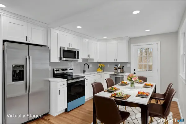 a kitchen with a refrigerator a stove a sink a dining table and chairs