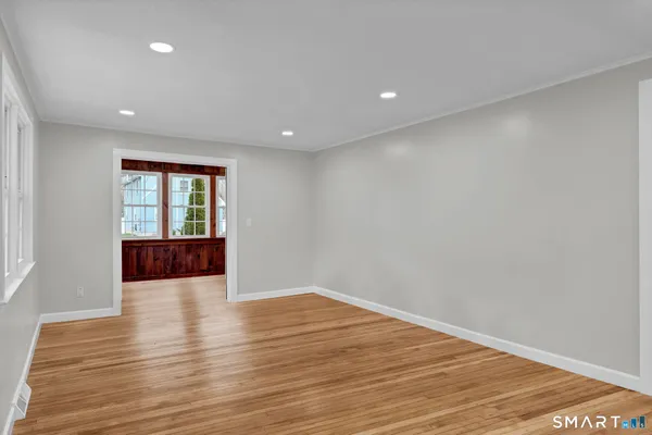 a view of an empty room with wooden floor and a window