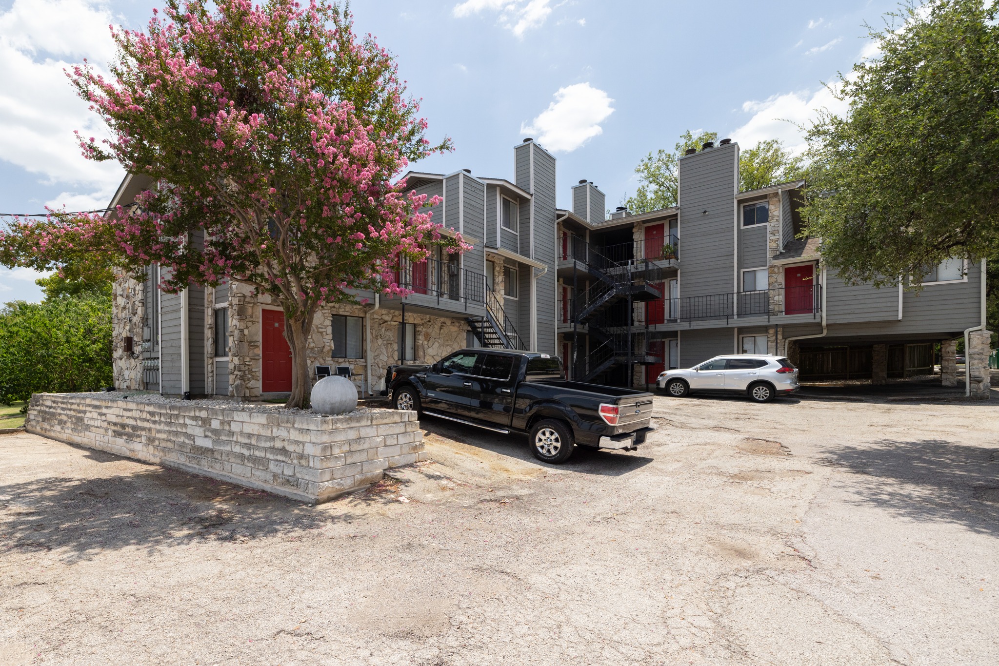 9079 Jollyville Road, Unit 301 Austin, TX 78759 - Photo 2 of 38 A flowering tree enhances the entrance of this multi-level residential building, offering a vibrant welcome.